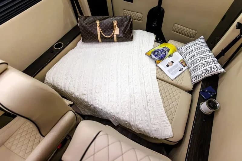 LuxShuttle interior — cream leather rear bench converted to lounge bed